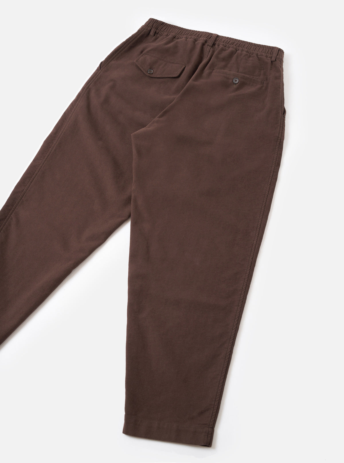 A rear view product shot of the Brown Comfort Moleskin Pleated Track Pant on a plain white background, displaying the two back pockets, clean waistband construction, and tapered leg silhouette in brown moleskin.
