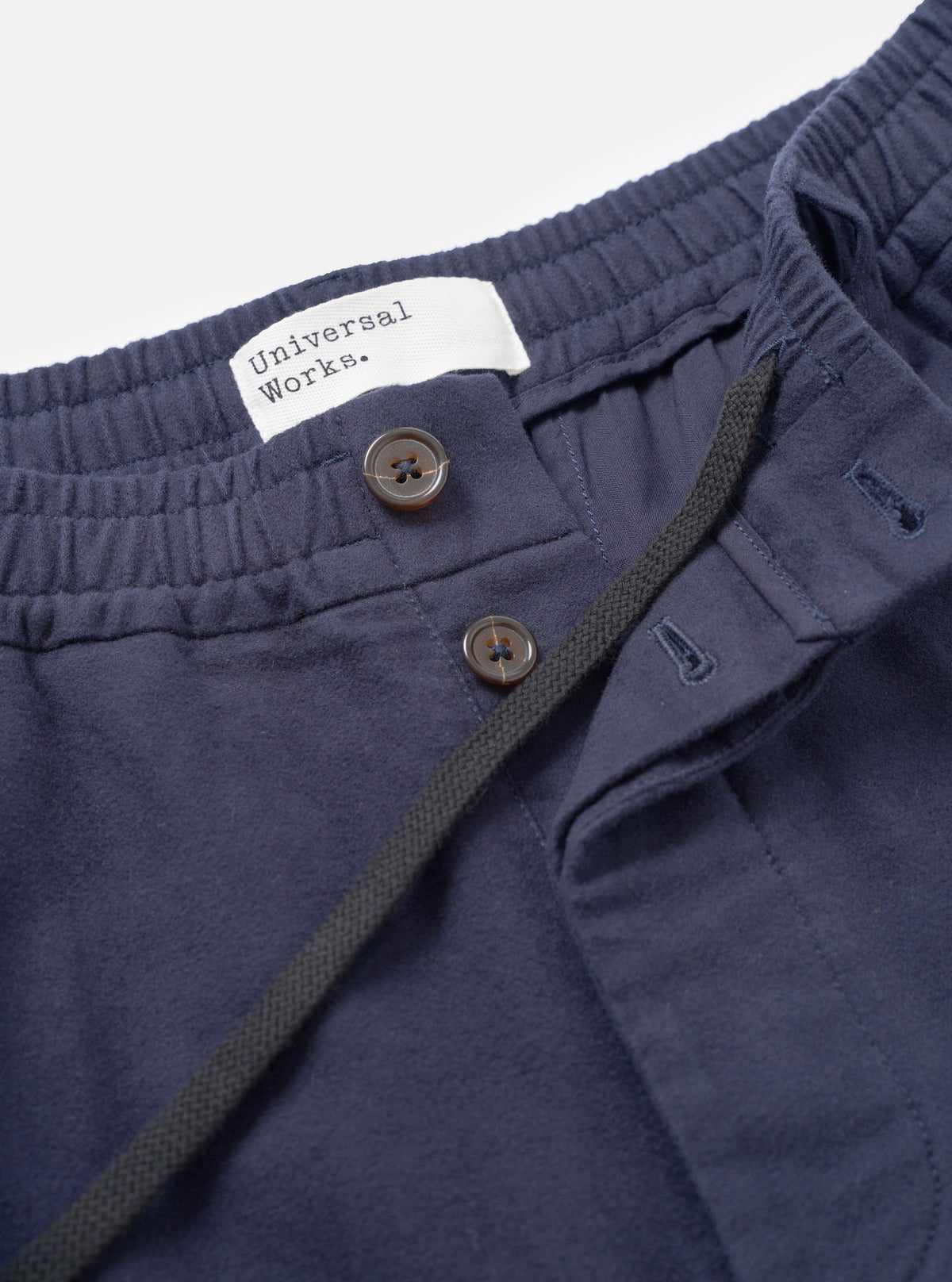 A close-up detail shot of the Navy Comfort Moleskin Pleated Track Pant on a plain white background, showing the waistband, drawstring cord, front single pleat, and deep navy cotton moleskin fabric texture.