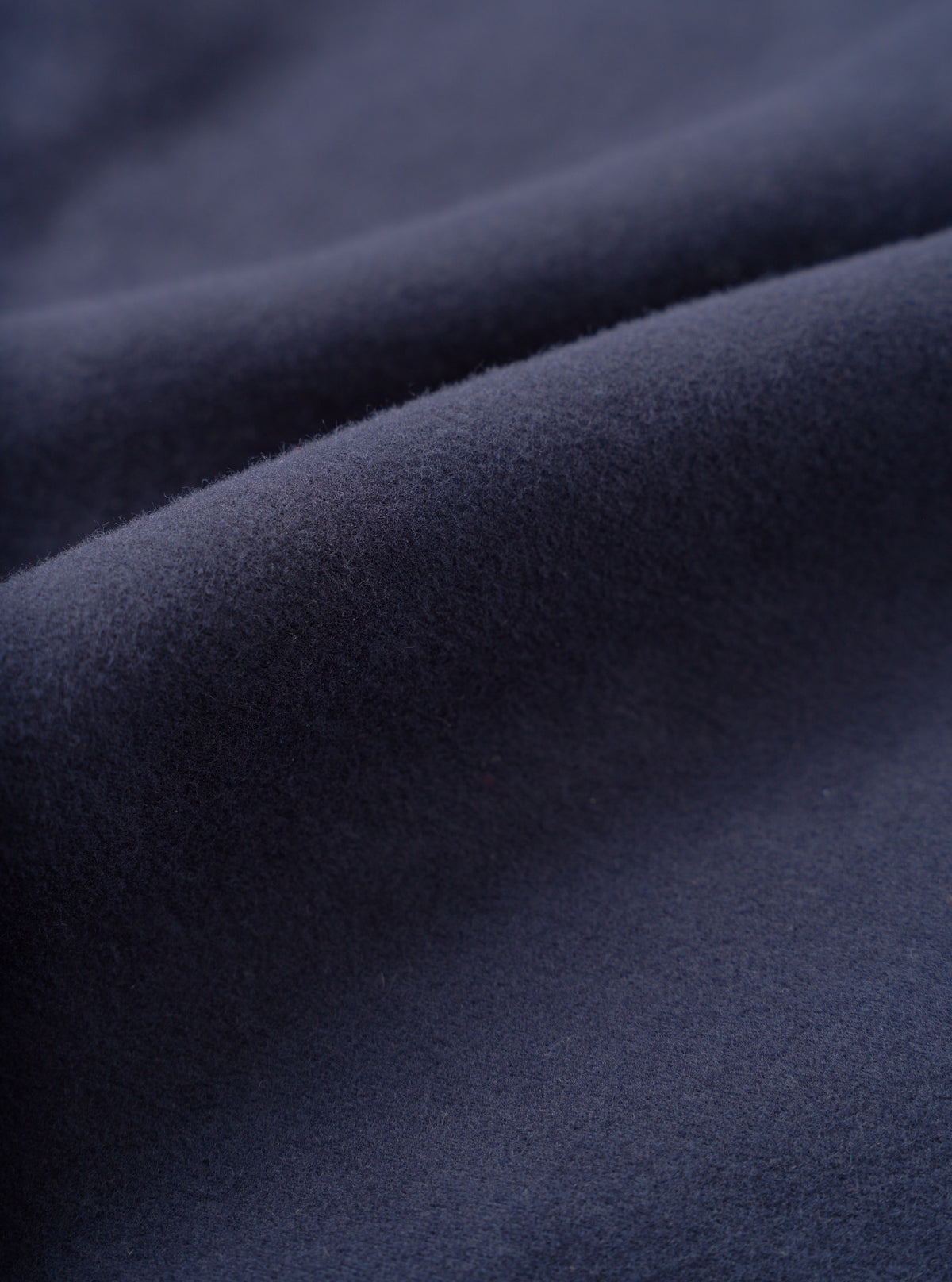 A detailed fabric swatch photo of the Navy Comfort Moleskin Pleated Track Pant on a plain white backdrop, highlighting the soft brushed finish and dense cotton canvas structure in dark navy blue.