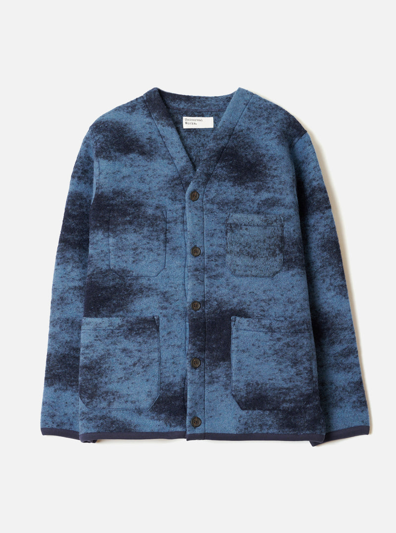 A front view of a model wearing the Blue Cloud Camo Knit Cardigan in a clean studio setting, showcasing the button front closure, cozy wool knit texture, and vibrant blue cloud camouflage pattern across the jacket.