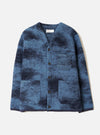 A front view of a model wearing the Blue Cloud Camo Knit Cardigan in a clean studio setting, showcasing the button front closure, cozy wool knit texture, and vibrant blue cloud camouflage pattern across the jacket.