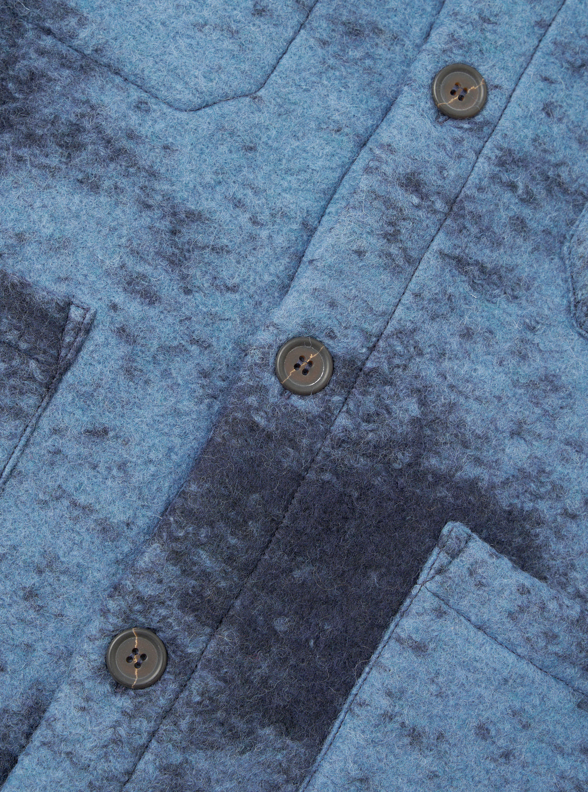 A close-up shot of a model wearing the Blue Cloud Camo Knit Cardigan, focusing on the button placket, neck collar, front patch pockets, and detailed cloud camo pattern in shades of blue knit wool fabric.