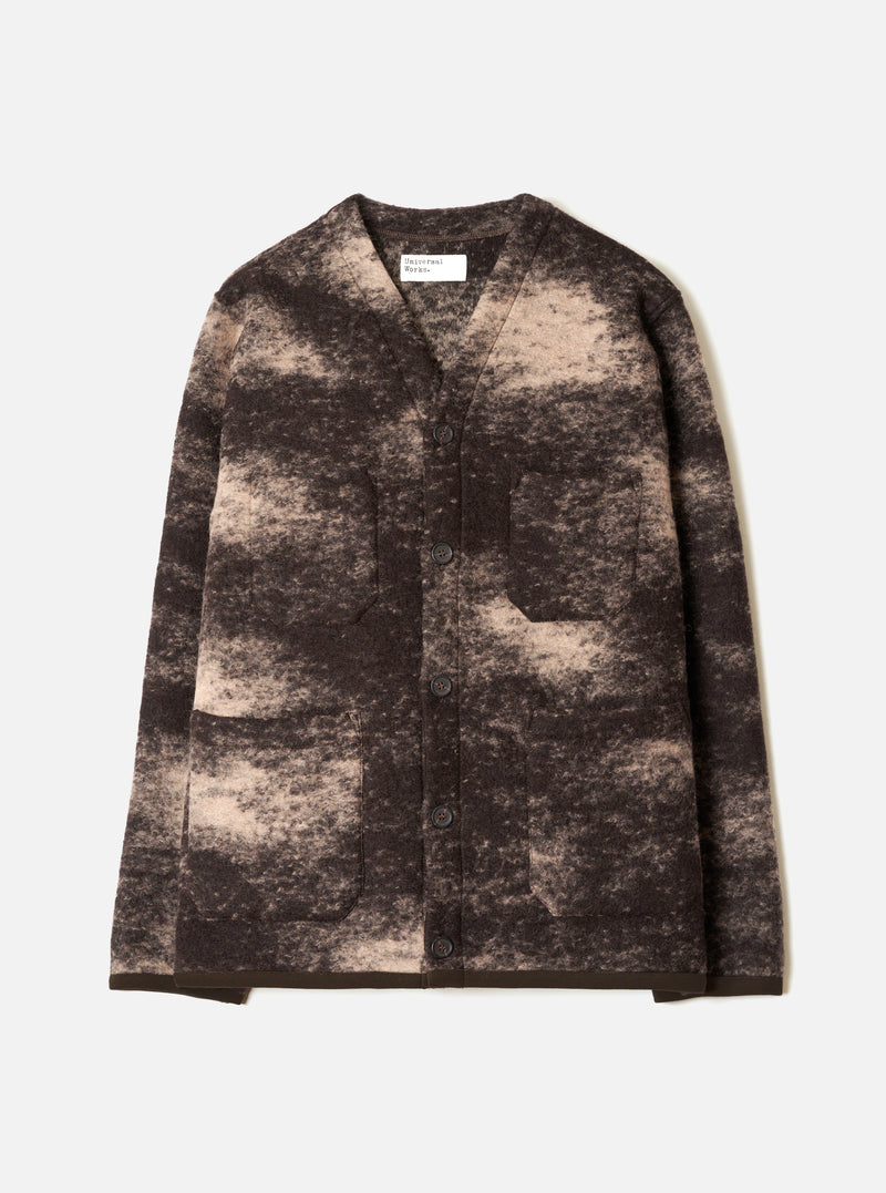 A front view of a model wearing the Brown Cloud Camo Knit Cardigan against a studio backdrop, displaying the button closure, front patch pockets, and distinct earthy brown cloud camo pattern throughout.