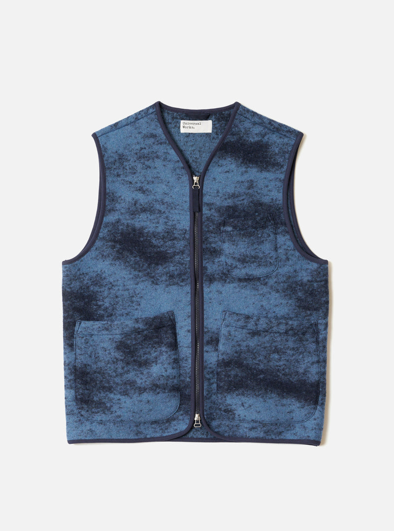 A full-length front view of a model wearing the Blue Cloud Camo Knit Zip Gilet in a studio shot, highlighting its full-zip front, sleeveless silhouette, collarless neck, and blue cloud camo pattern.