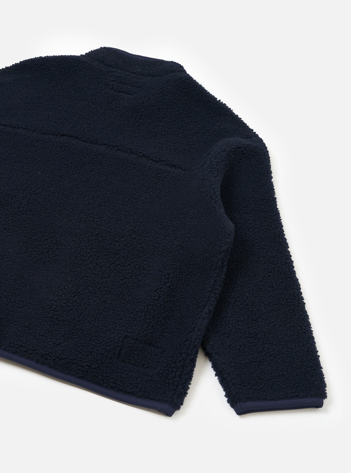 Rear view of the Navy Artic Fleece Hep Mountain Jacket laid out against a plain light background, highlighting the clean back panel construction, soft fleece texture, and durable hem finish.