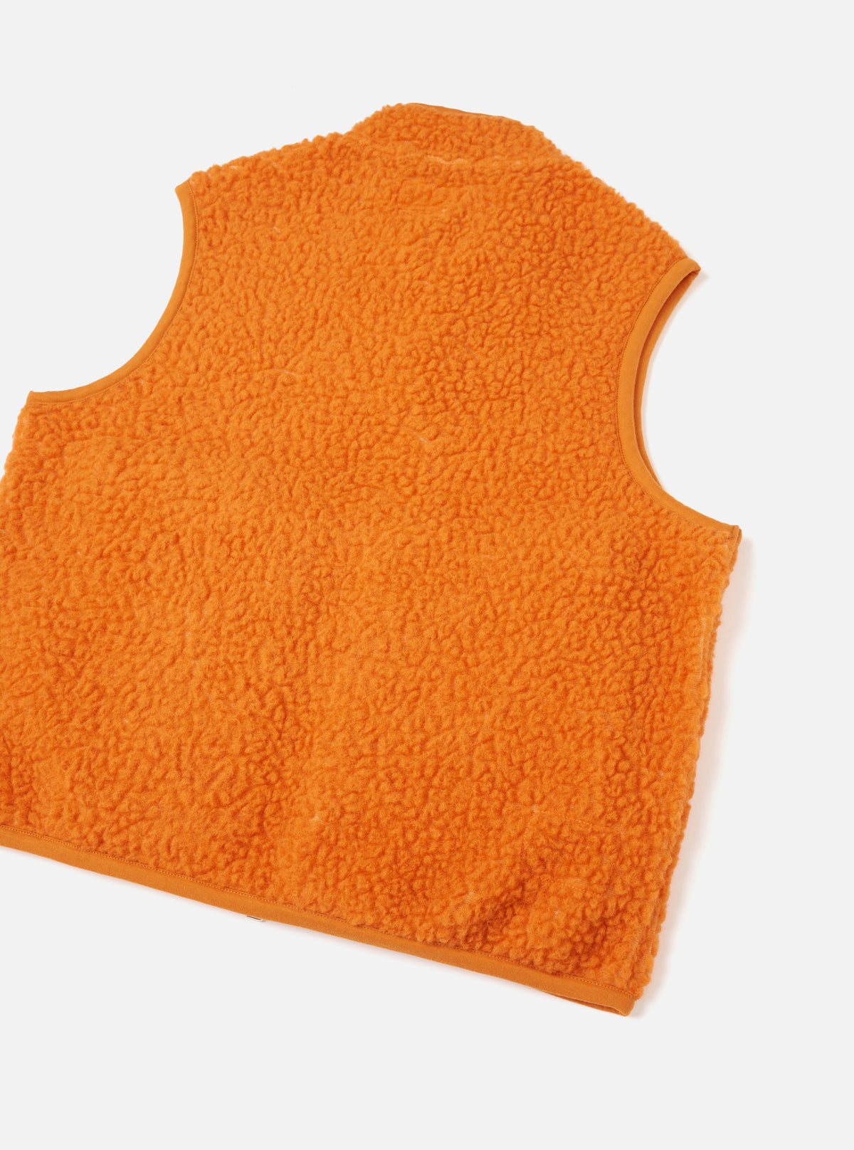 A back view of a model wearing the Orange Artic Fleece Hep Mountain Gilet standing against a neutral studio backdrop, showing the overall fit, hem cut, and bright orange fleece material across the back panel.