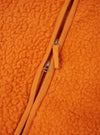 A detailed close-up shot of a model wearing the Orange Artic Fleece Hep Mountain Gilet, focusing on the collar, zip closure, and rich textured fleece weave in bright orange against a simple studio background.