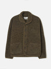 Brown boucle style fleece Lancaster jacket laid flat on a light grey studio backdrop. Shawl collar with tonal brown knit trim edging the front placket, cuffs, and hem. Four dark buttons fasten the centre front. Two large patch pockets sit at the lower front. Universal Works woven label visible at the neck.