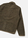 Back view of a brown boucle style fleece Lancaster jacket, laid flat on a white studio surface. The textured, looped fleece fabric shows a mottled brown and dark grey tone. A tan grosgrain trim edges the collar, cuffs, and straight hem. One sleeve extends to the right.