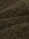 Close-up of the brown boucle style fleece fabric used in the Lancaster Jacket. The texture shows dense, tightly looped fibres with a mix of dark brown and tan tones, creating a coarse, woolly surface. The fabric is folded to reveal its thick, plush depth against a neutral studio background.
