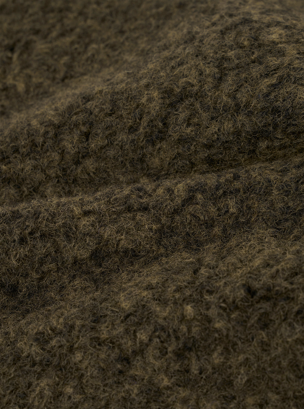 Close-up of the brown boucle style fleece fabric used in the Lancaster Jacket. The texture shows dense, tightly looped fibres with a mix of dark brown and tan tones, creating a coarse, woolly surface. The fabric is folded to reveal its thick, plush depth against a neutral studio background.