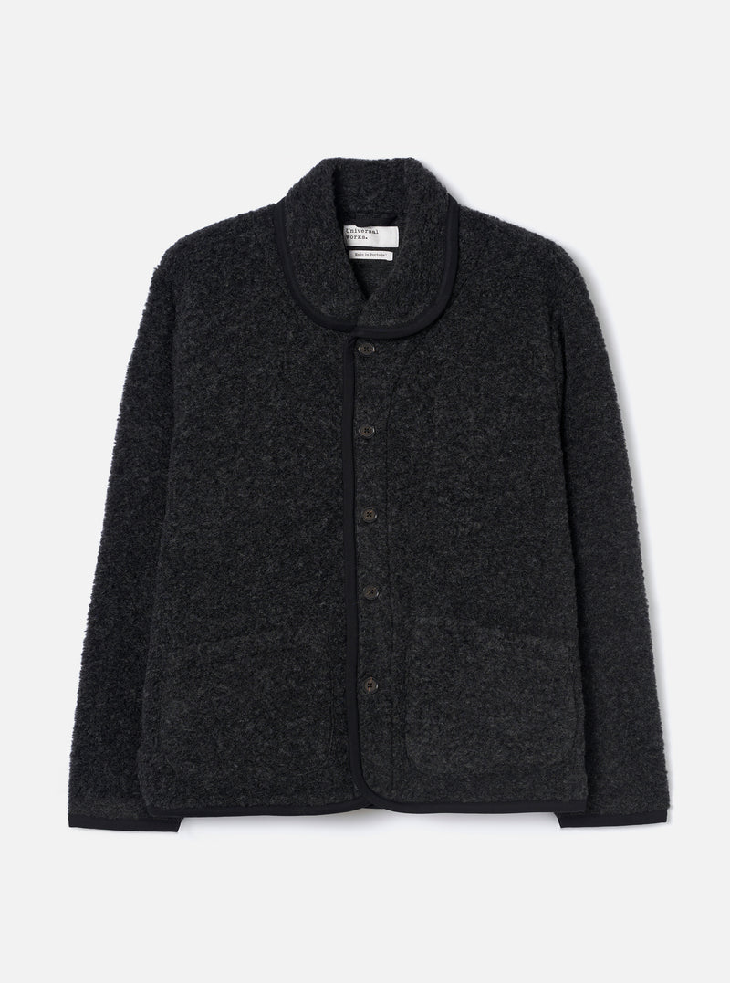 Charcoal boucle style fleece Lancaster jacket laid flat on a light grey studio backdrop. Features a shawl collar with black trim, five-button front placket, two large patch pockets, and a ribbed hem. The textured boucle style fabric has a looped, marl appearance throughout.