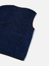 Close-up flat lay of a blue boucle style fleece gilet on a light grey seamless backdrop. The textured, looped boucle style fabric is visible across the body, with a navy binding trim running along the armhole and neckline edges. The hem and lower body are cropped into frame at an angle.