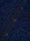 Close-up of the blue boucle style fleece Lancaster gilet, showing three dark four-hole buttons fastened along a navy grosgrain placket. The textured boucle style fabric has a looped, flecked surface in cobalt and dark navy tones. No model or mannequin is present.