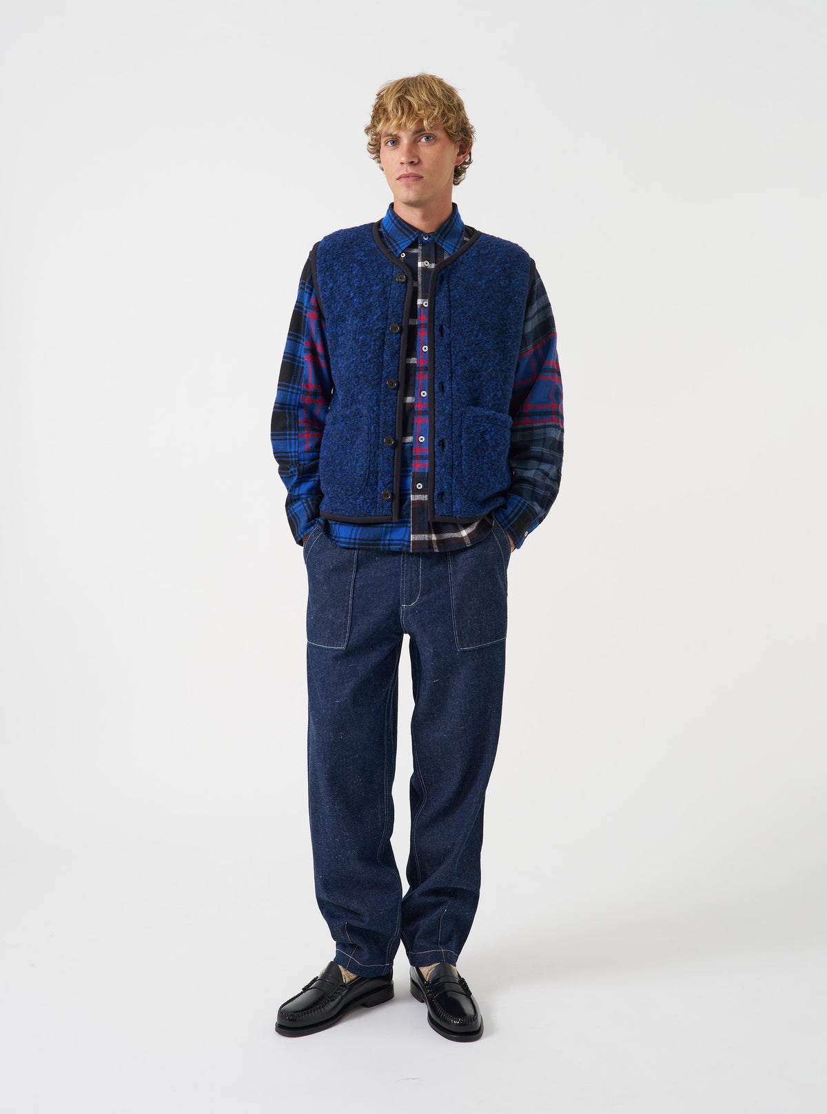 Front full-length view of a model wearing the Blue Bouclet Fleece Lancaster Gilet over a shirt against a neutral background. The image highlights the sleeveless design, buttoned front, and cozy textured fleece fabric.