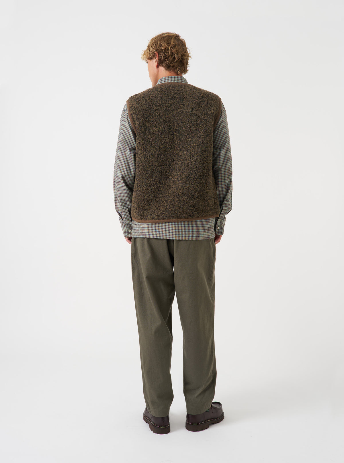 Back view of a model wearing the Brown Bouclet Fleece Lancaster Gilet against a minimal light background. The photograph highlights the overall fit, straight hem, and distinct textured finish of the brown fleece fabric.
