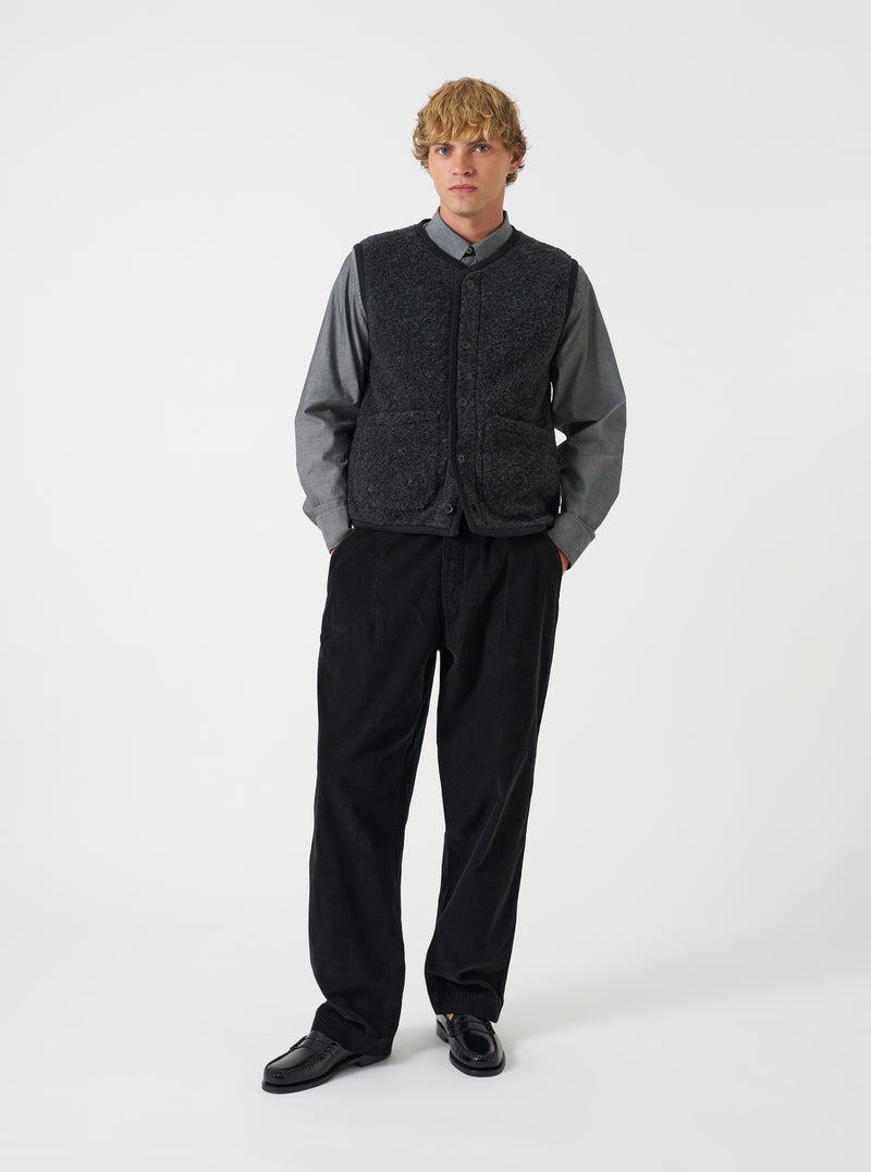 Front view of a model wearing the Charcoal Bouclet Fleece Lancaster Gilet in a bright studio environment. The shot emphasizes the dark grey fleece texture, central button closure, V-neckline, and practical front pockets.