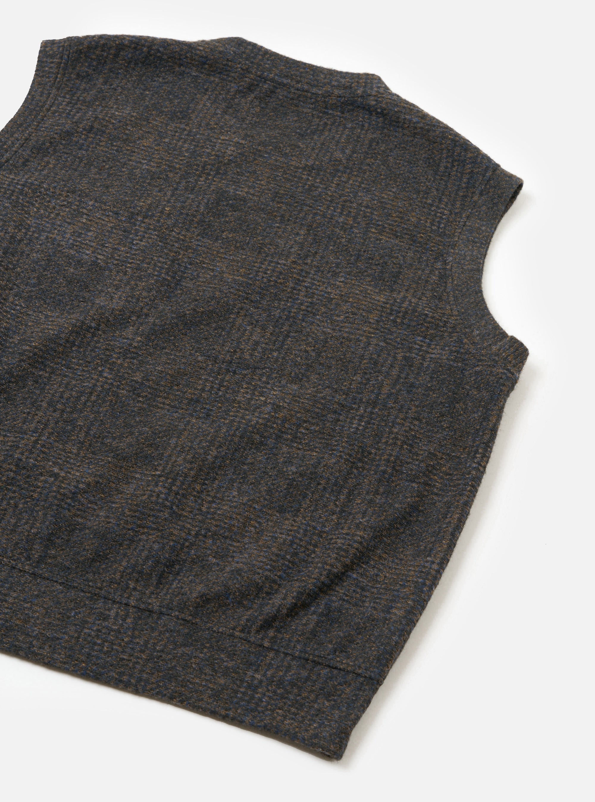 Navy sleeveless crew knit in a dark navy, brown and grey Glen plaid pattern. Flat lay on a white surface, shot at an angle showing the back panel, armhole, and ribbed hem. The wool-blend fabric has a textured, lightly mottled finish with a large-scale check woven throughout.