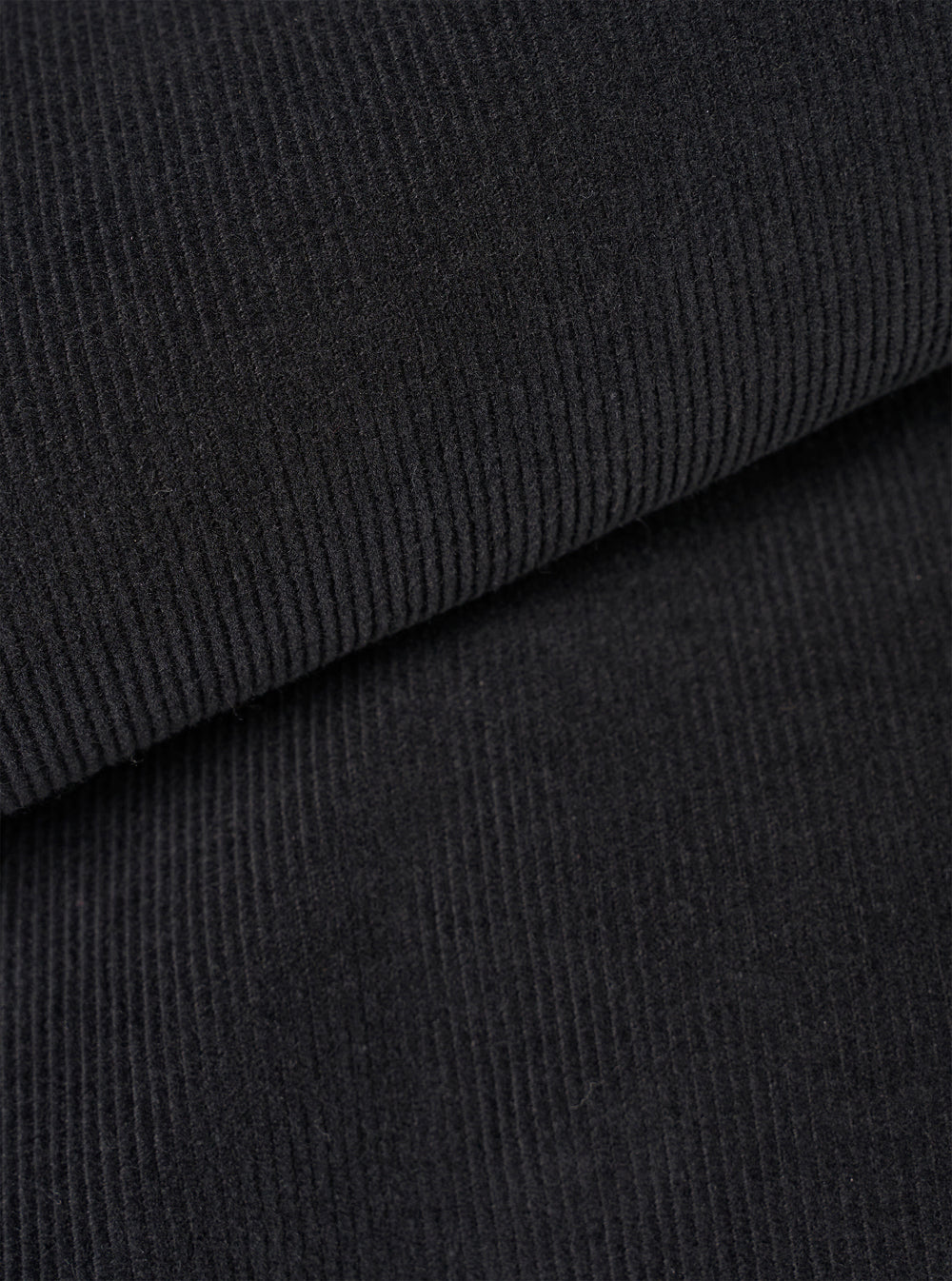 Close-up fabric swatch image of the Black Fine Cord Bakers Overshirt on a white background, detailing the distinct narrow ridges, soft texture, and deep black shade of the fine corduroy cotton material.