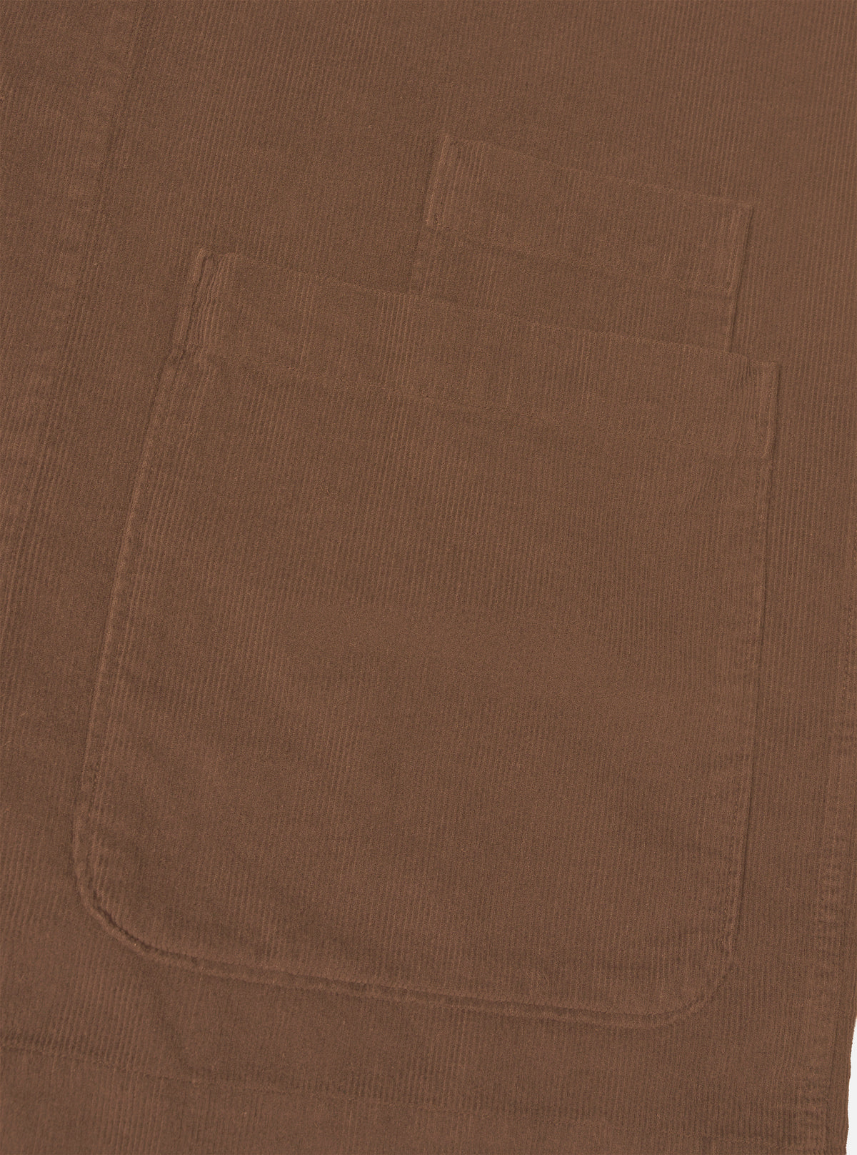 A detailed close-up shot of the Universal Works Brown Fine Cord Bakers Overshirt on a plain white background, highlighting the fine-wale corduroy texture, front patch pocket, and tonal button placket.
