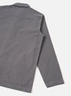 Back view of a male model wearing the Universal Works Grey Fine Cord Bakers Overshirt, displaying the relaxed fit, straight cut hem, and soft corduroy drape against a plain, minimal background.