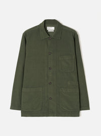 A male model wearing the Universal Works Olive Fine Cord Bakers Overshirt, shown from the front against a plain white background, highlighting its relaxed fit, front patch pockets, and fine corduroy texture.