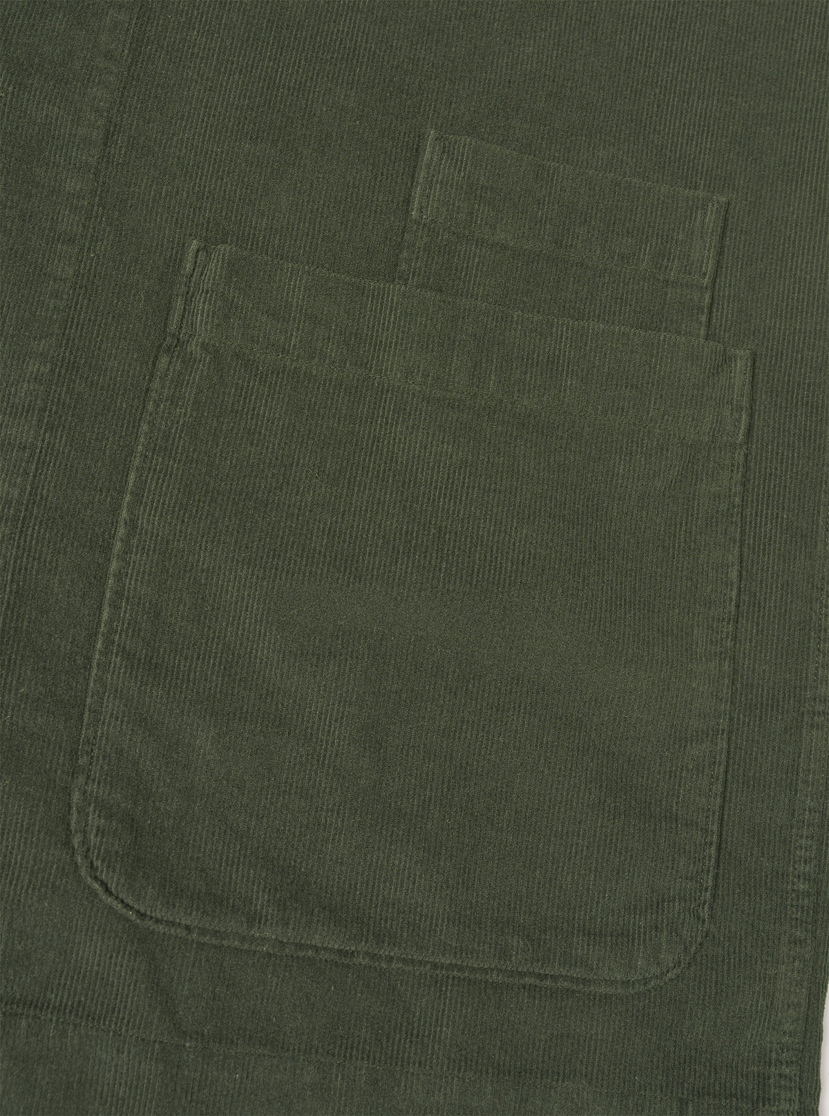 A close-up detail shot of the Universal Works Olive Fine Cord Bakers Overshirt on a plain white background, highlighting the fine-wale cotton corduroy texture, front buttons, and chest pocket.