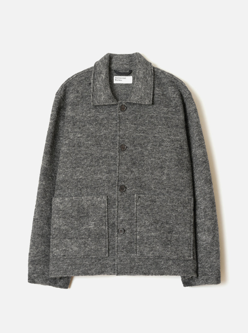 A male model wearing the Universal Works Grey Marl Wool Mix Knit Rams Jacket, standing against a plain neutral background, highlighting the full-zip closure, collar, and grey marl knit texture.
