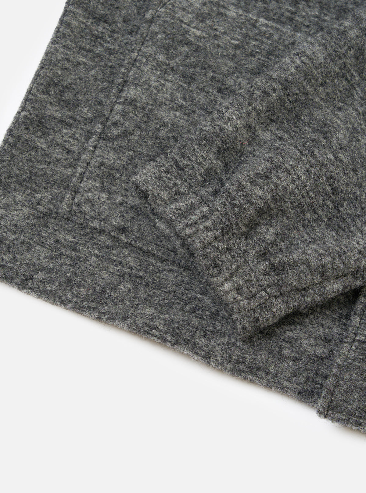 A close-up shot of the Universal Works Grey Marl Wool Mix Knit Rams Jacket on a plain background, displaying the zipper detail, soft fleece collar, and textured wool blend knit pattern.
