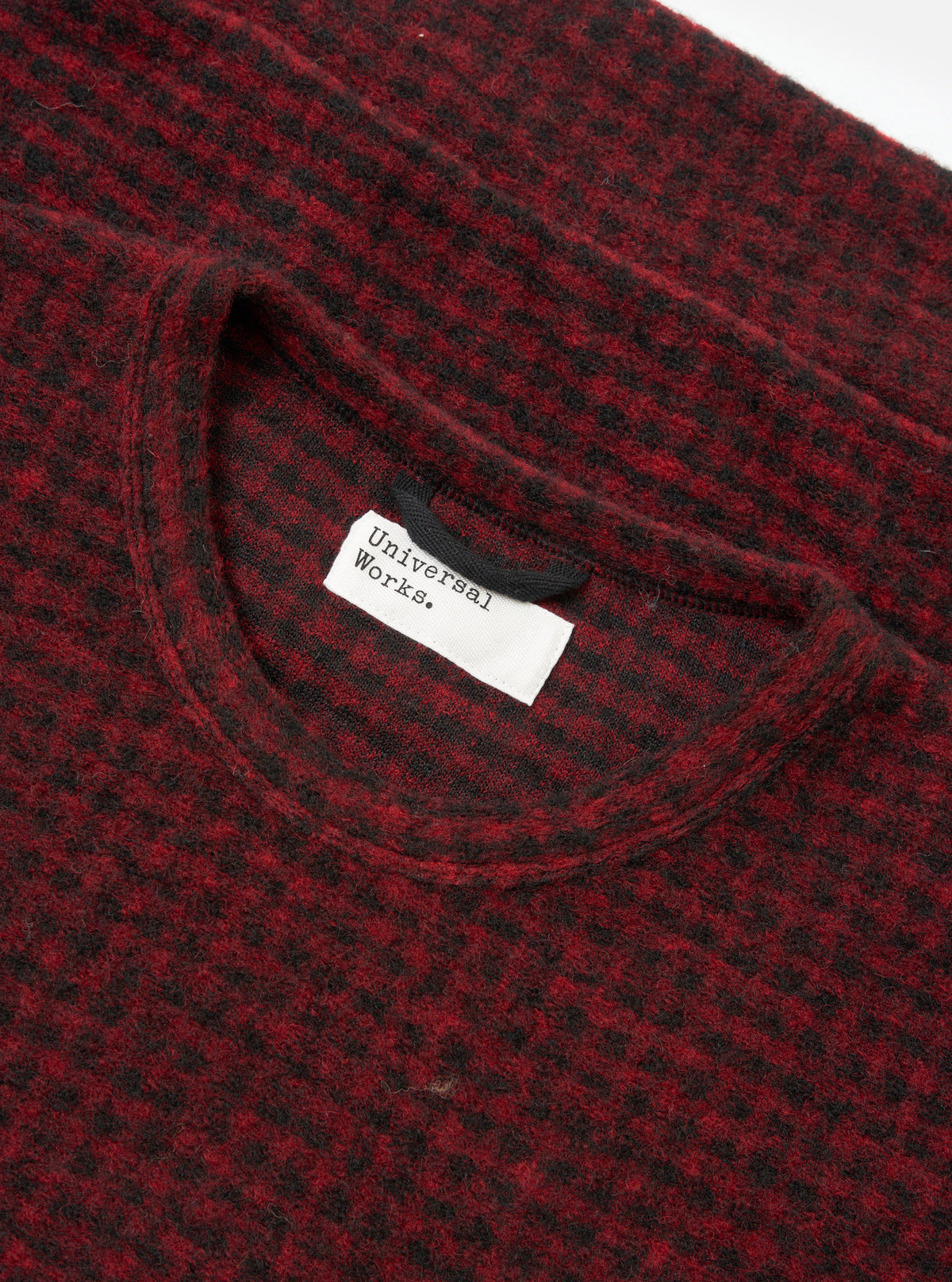 A close-up view of a model wearing the Black/Red 533 Wool Mix Giacomo Tank Top, focusing on the neck trim, armhole cut, and striking black and red woven wool pattern in a studio environment.