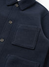 A detailed close-up shot of the Navy Techno Melton Plain Tag Jacket on a white background, featuring the pocket construction, fine stitching, tag detail, and dark navy polyester-wool blend fabric texture.