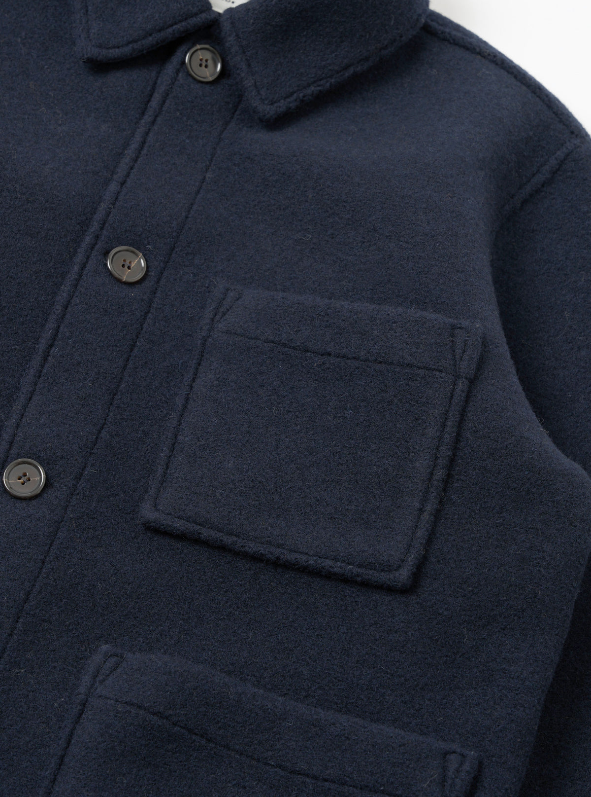 A detailed close-up shot of the Navy Techno Melton Plain Tag Jacket on a white background, featuring the pocket construction, fine stitching, tag detail, and dark navy polyester-wool blend fabric texture.