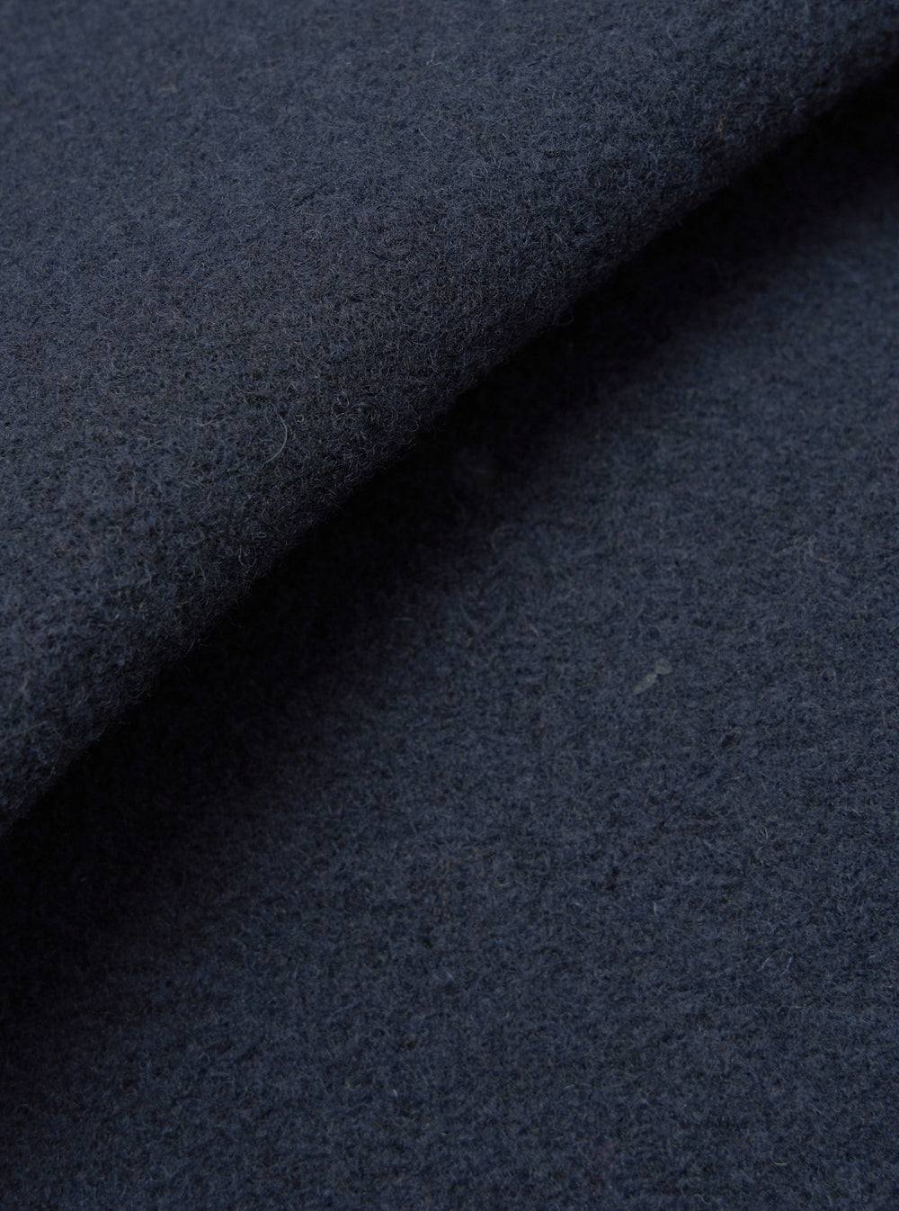 A macro fabric swatch shot of the Navy Techno Melton Plain Tag Jacket set against a plain white backdrop, highlighting the tight weave, matte surface finish, and deep navy hue of the techno melton material.
