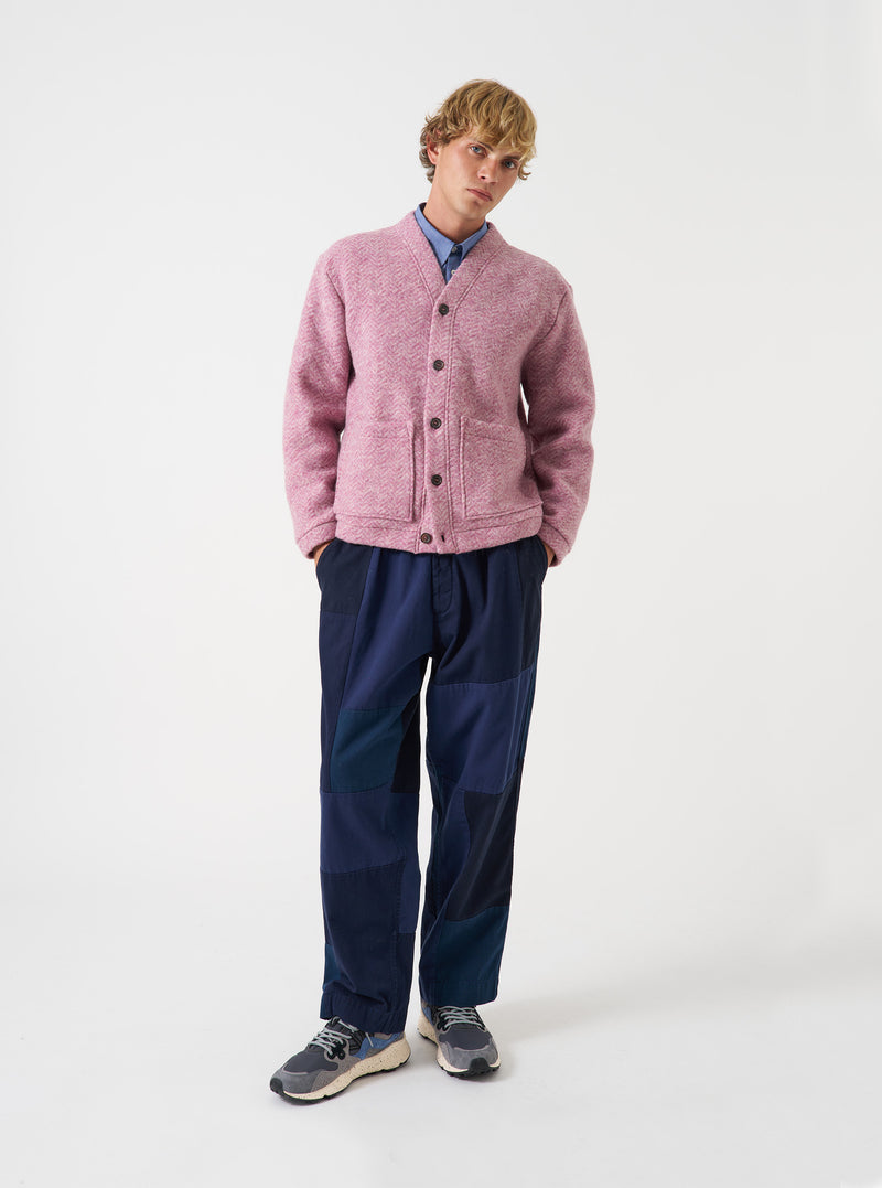 A full-length photograph of a model wearing the Pink Raven Fleece Advance Cardigan in a studio setting, demonstrating its relaxed fit, front buttoning, and vibrant pink wool fleece fabric against a neutral backdrop.