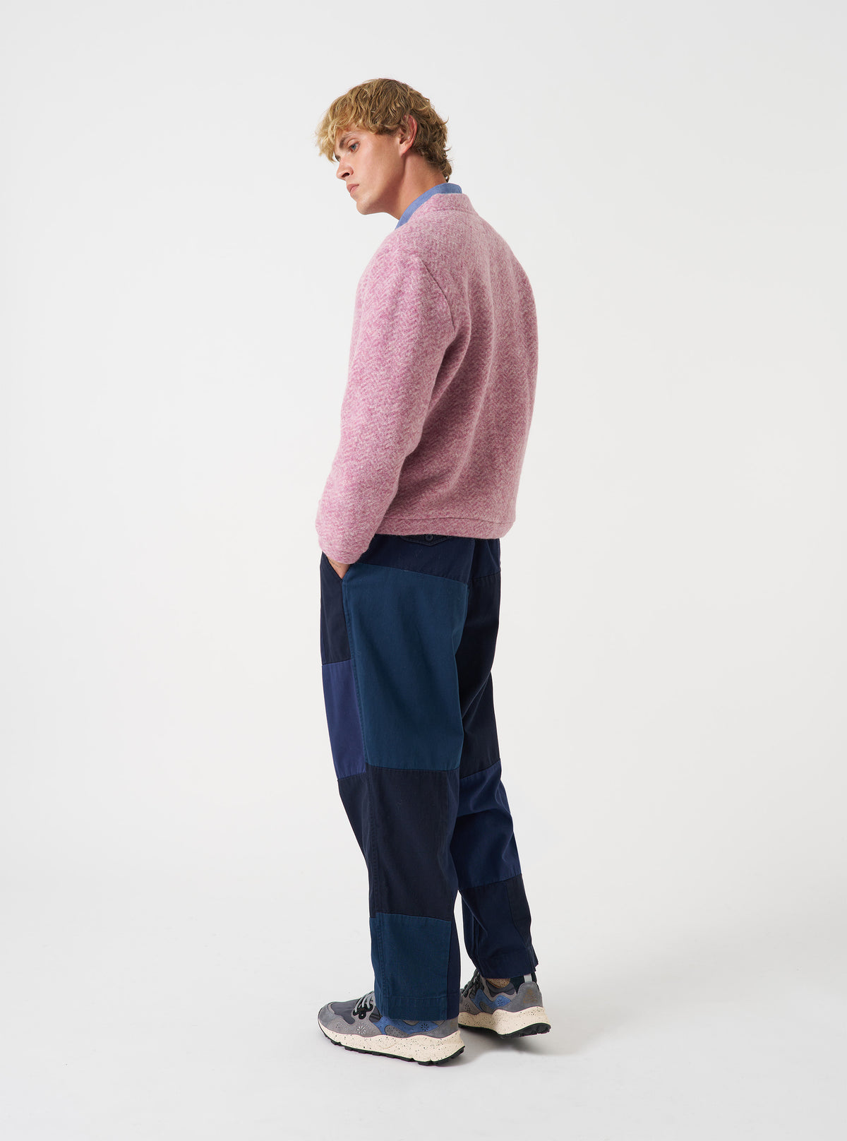 An angled studio photograph of a model wearing the Pink Raven Fleece Advance Cardigan against a plain neutral backdrop, highlighting the comfortable drape, sleeve length, and rich pink raven fleece texture.