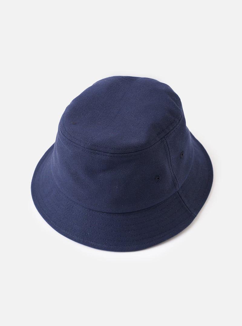 A side profile shot of the Navy Canvas Lewis Hat set against a plain light studio backdrop, showcasing the crown structure, embroidered ventilation eyelets, and durable navy blue canvas fabric.