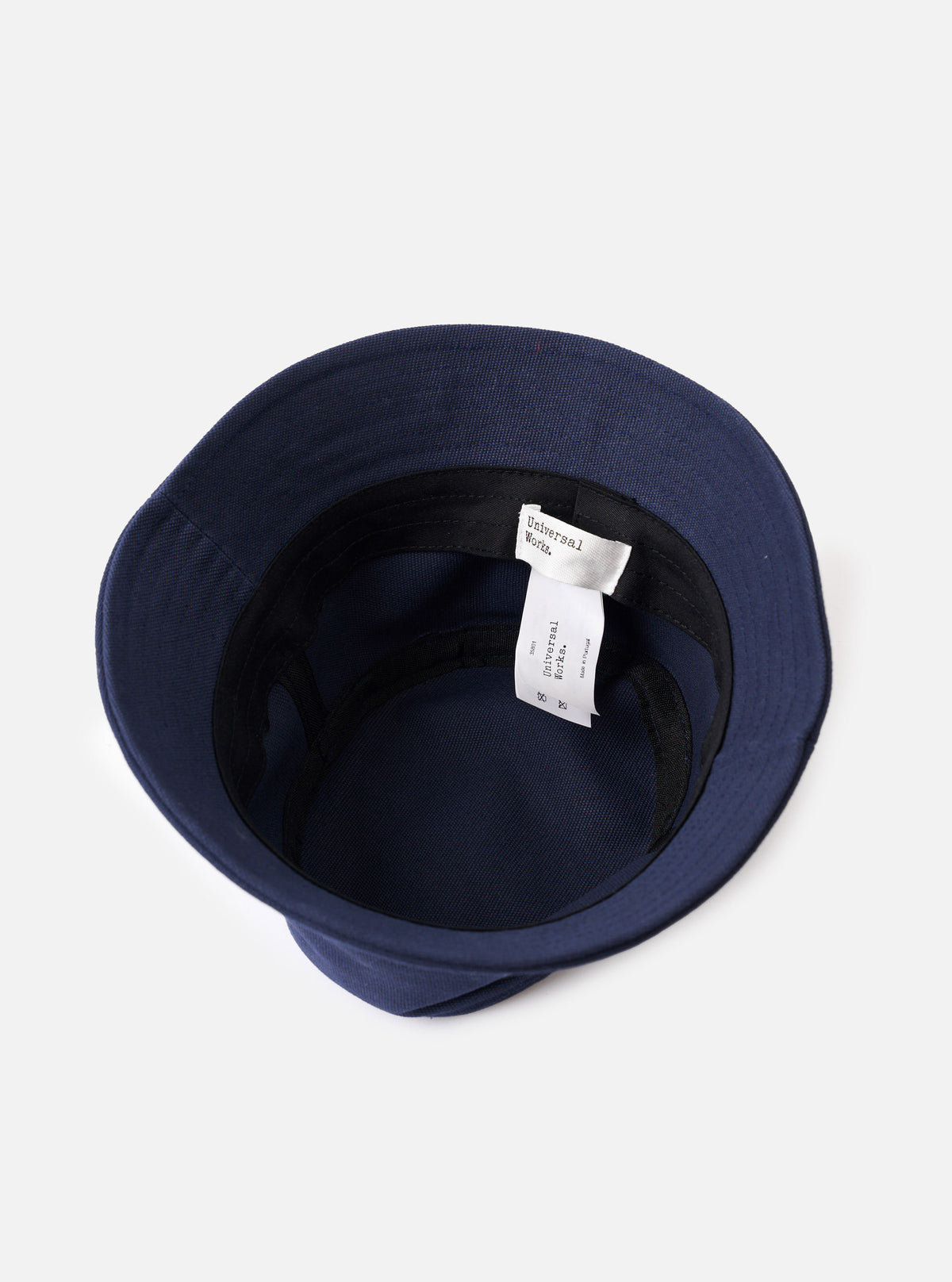 A close-up detail view of the Navy Canvas Lewis Hat against a plain studio backdrop, highlighting the embroidered eyelets, fine stitching details along the brim, and sturdy navy cotton fabric texture.