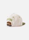 A close-up detail shot of the Ecru/Olive Canvas Baseball Hat set against a white background. The photograph highlights the durable cotton canvas texture, neat seam paneling, and ventilation eyelet.