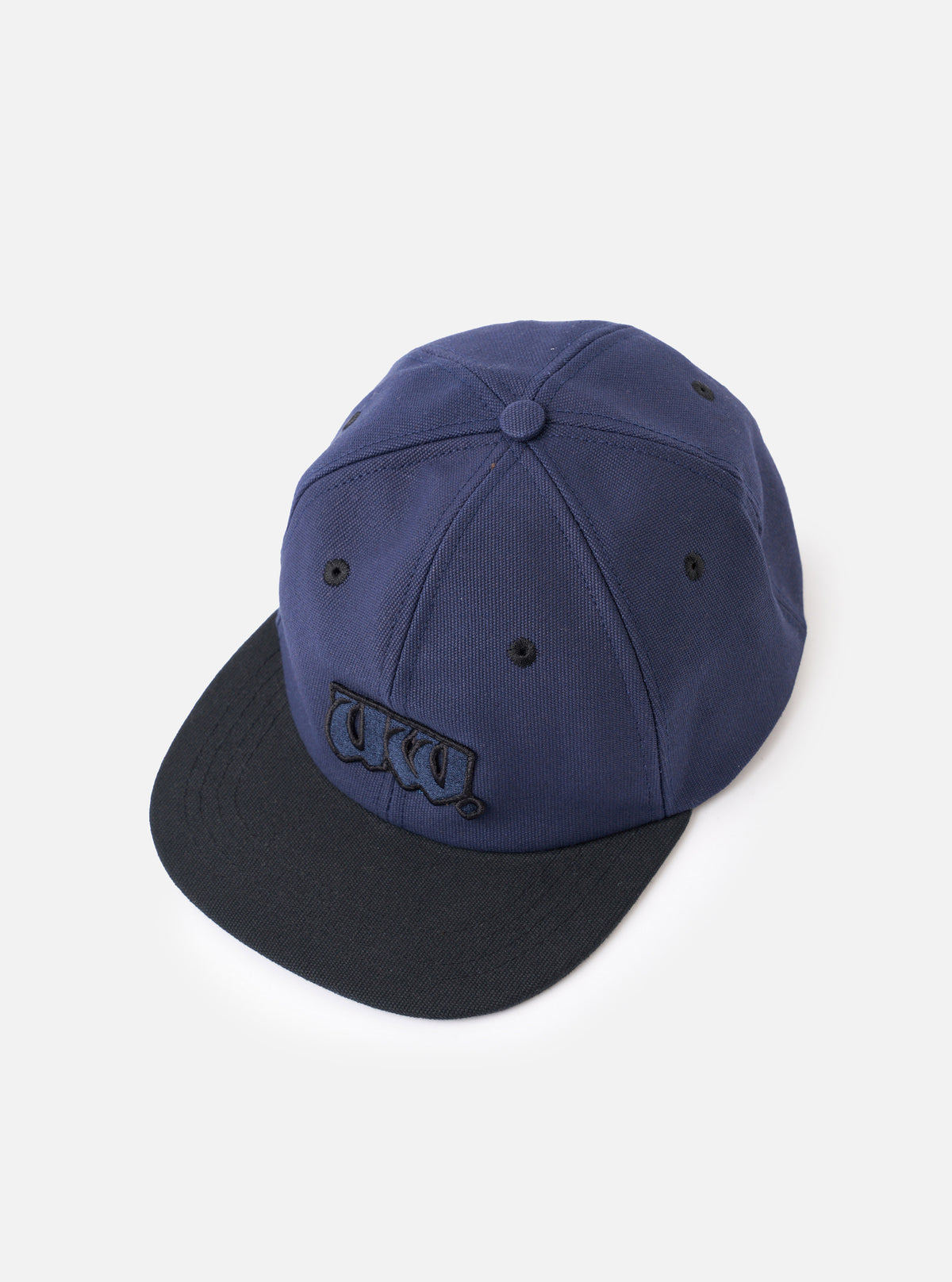 A side profile view of the Navy/Black Canvas Baseball Hat shown on a plain white background. The image displays the structured navy cotton canvas crown, prominent black peak, and ventilation eyelets.
