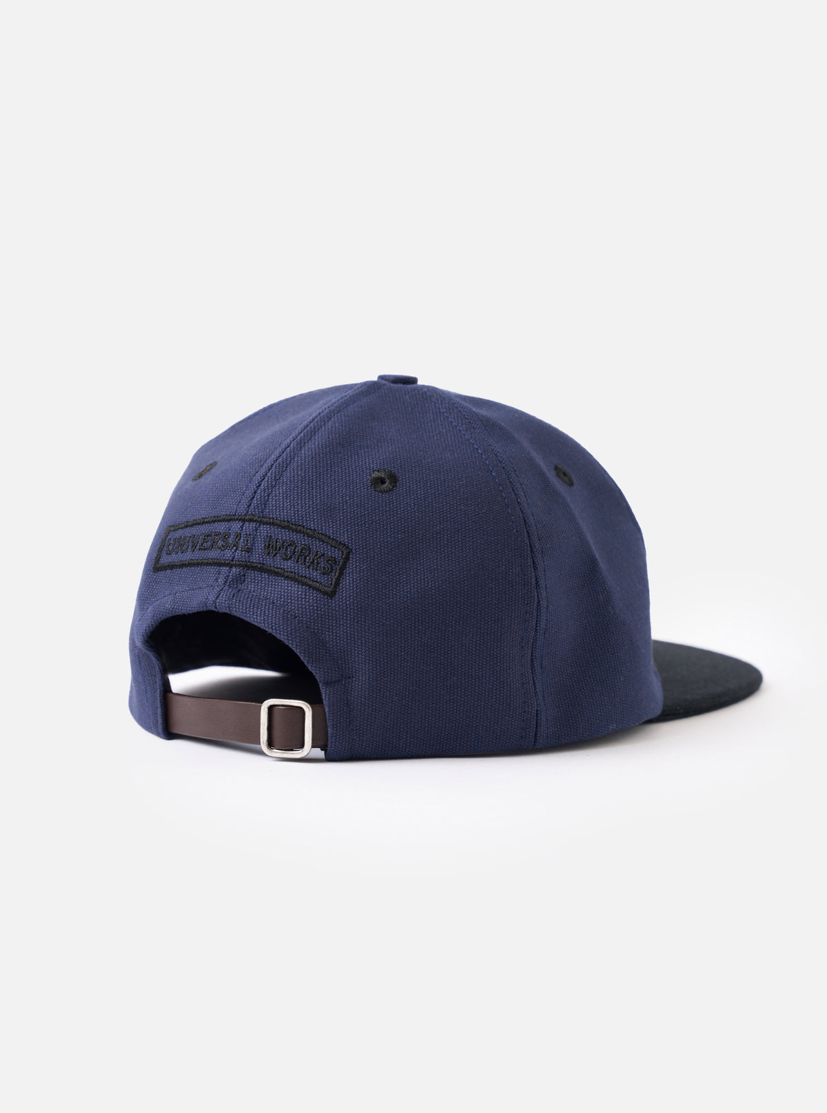 A close-up detail shot of the Navy/Black Canvas Baseball Hat displayed on a white background. The photo highlights the durable navy canvas fabric texture, precise panel stitching, and metal eyelet detail.