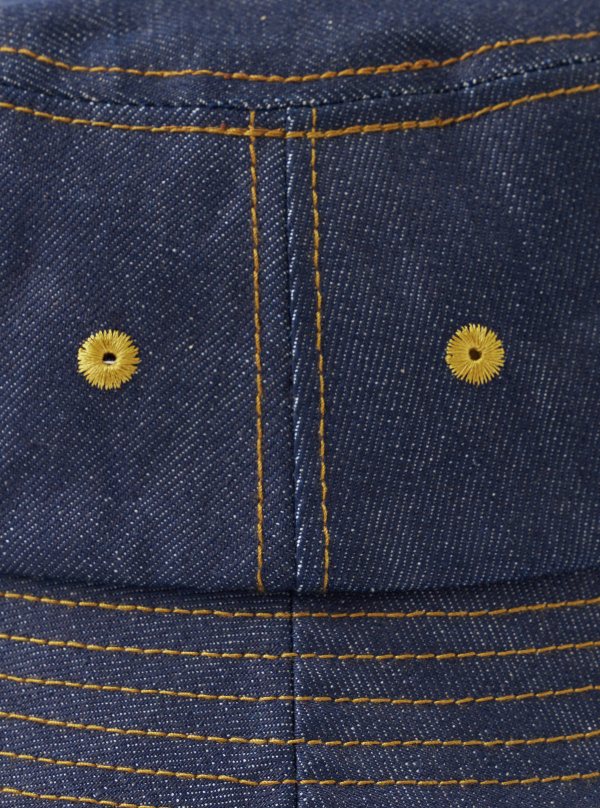 A top-down view of the Indigo 13oz Selvedge Denim Lewis Hat against a plain white background, showcasing the circular crown paneling, top stitching details, and dark blue organic cotton selvedge denim texture.