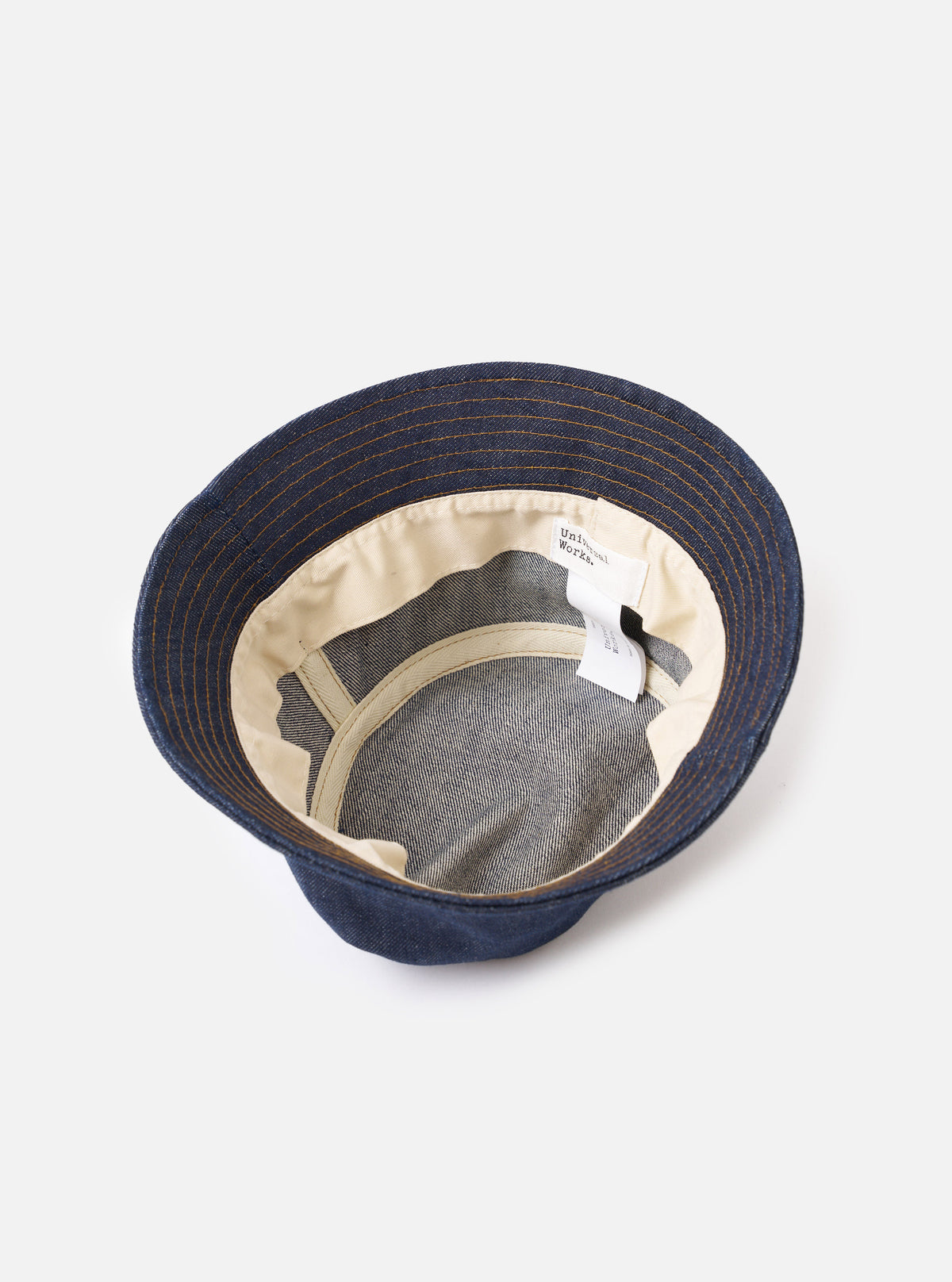 An interior view of the Indigo 13oz Selvedge Denim Lewis Hat on a white studio background, displaying the internal head tape, red selvedge seam detail, and clean inner construction of the dark blue bucket hat.