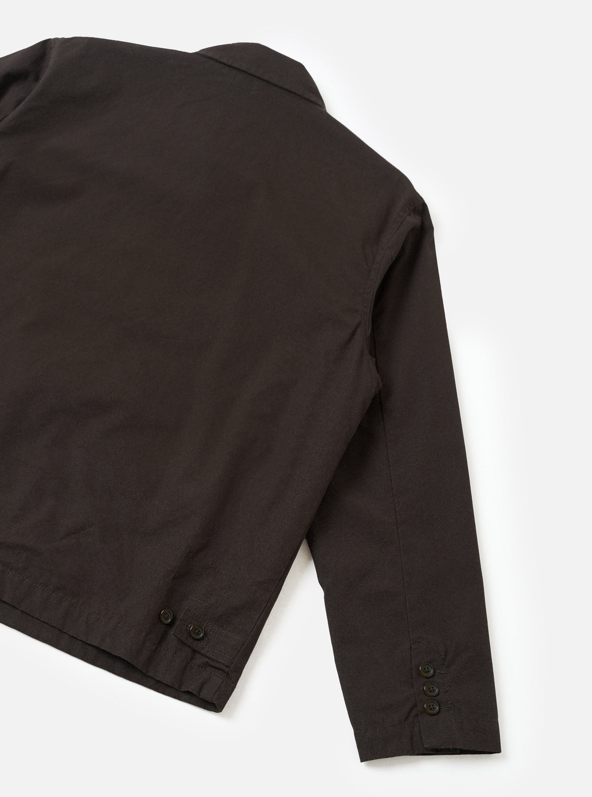 A back view studio photograph of the Brown Micro Canvas Warmus Jacket set against a plain white backdrop, highlighting the clean shoulder yoke, straight hem cut, and durable brown cotton micro canvas fabric.