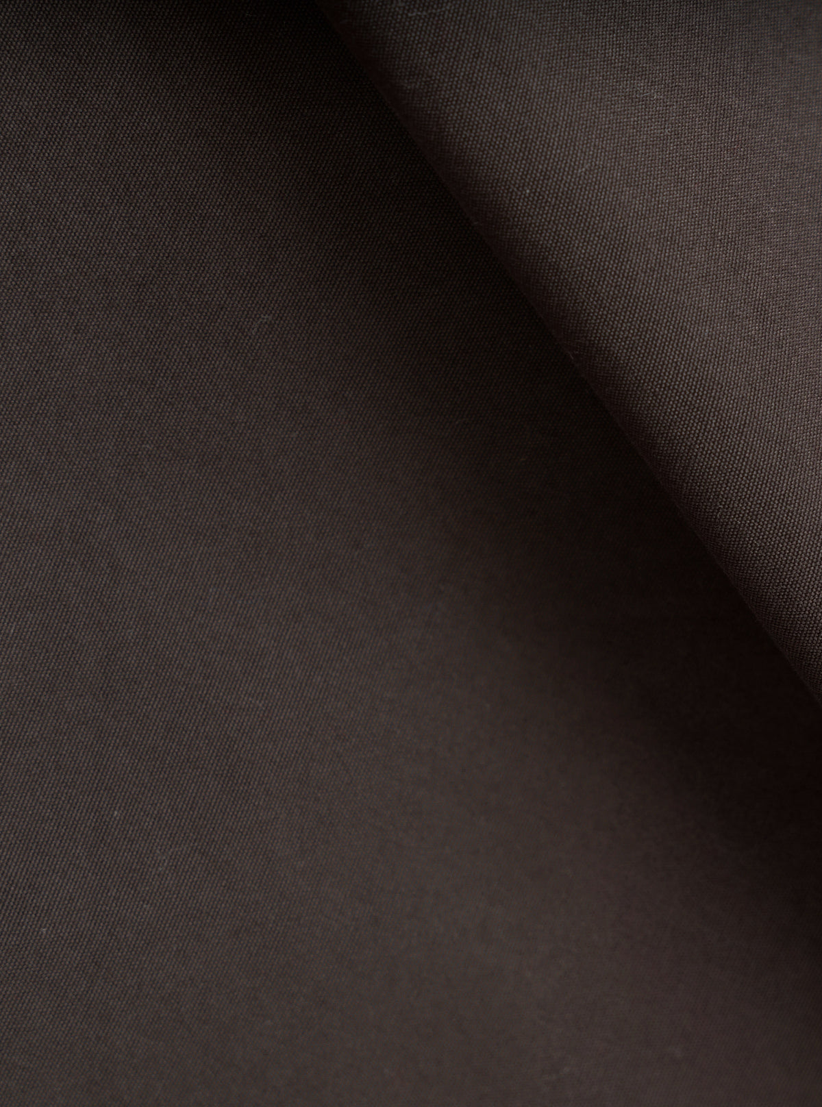 A close-up fabric swatch image of the Brown Micro Canvas Warmus Jacket on a plain white background, showing the fine weave texture, smooth surface finish, and rich shade of the brown cotton canvas material.