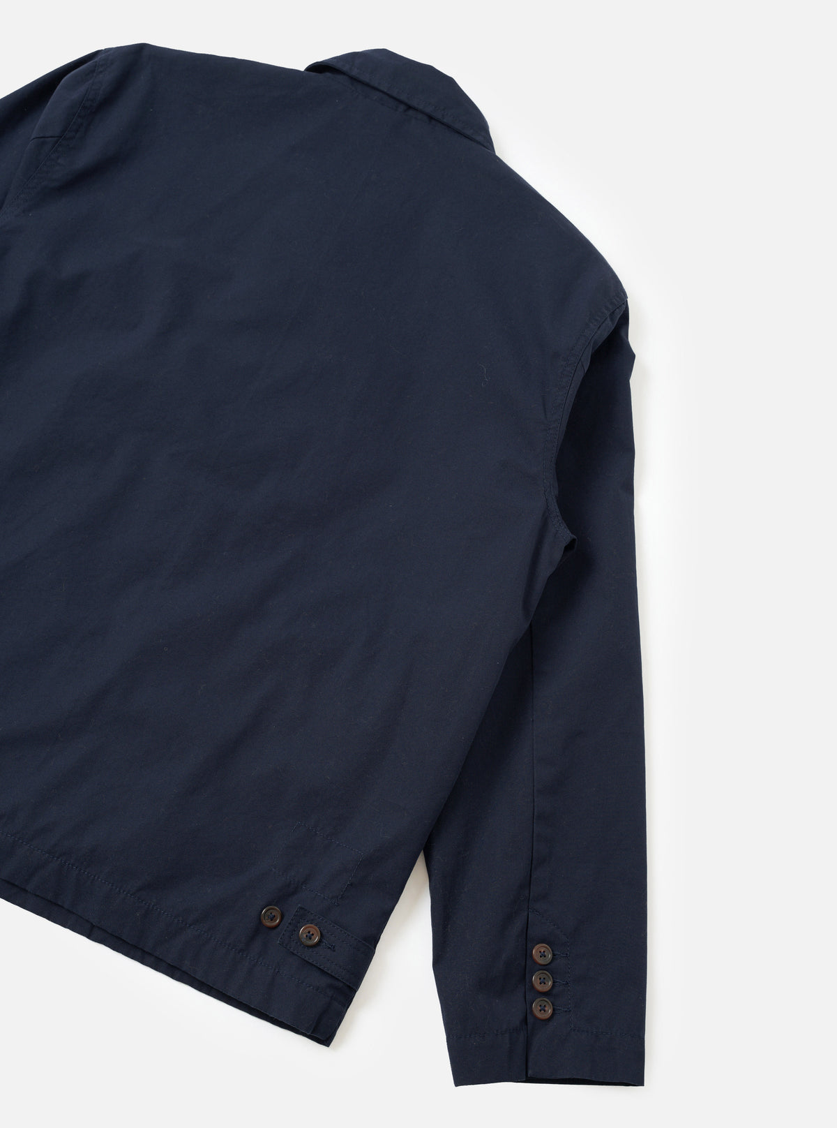 A rear perspective studio photograph of the Navy Micro Canvas Warmus Jacket against a clean white backdrop, showcasing the smooth back construction, shoulder seam stitching, and dark navy cotton canvas material.