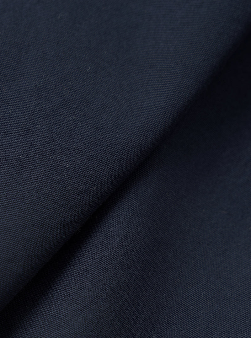 A close-up fabric swatch shot of the Navy Micro Canvas Warmus Jacket on a plain white background, highlighting the fine weave, subtle texture, and deep dark navy blue color of the cotton canvas material.