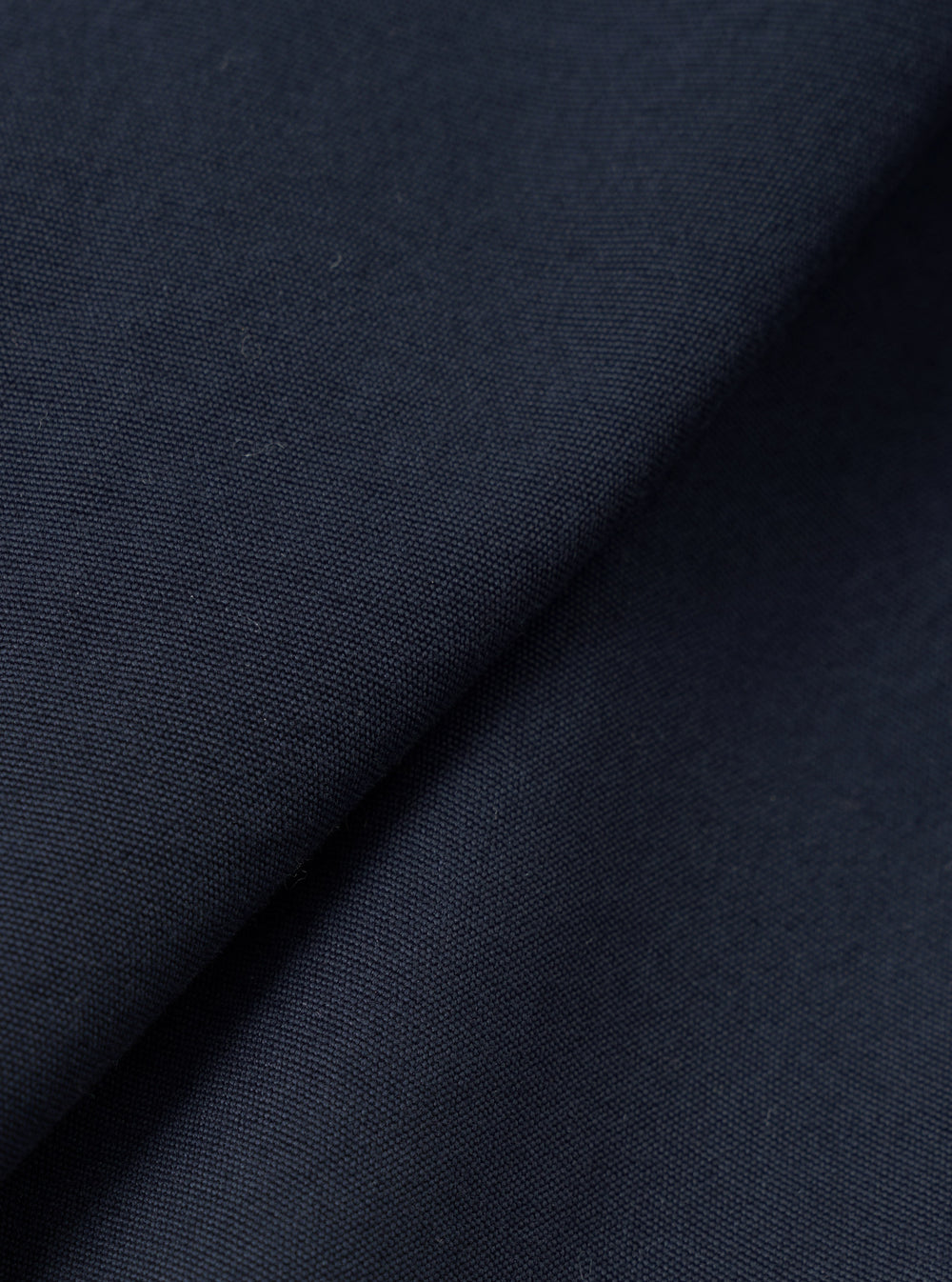 A close-up fabric swatch shot of the Navy Micro Canvas Warmus Jacket on a plain white background, highlighting the fine weave, subtle texture, and deep dark navy blue color of the cotton canvas material.