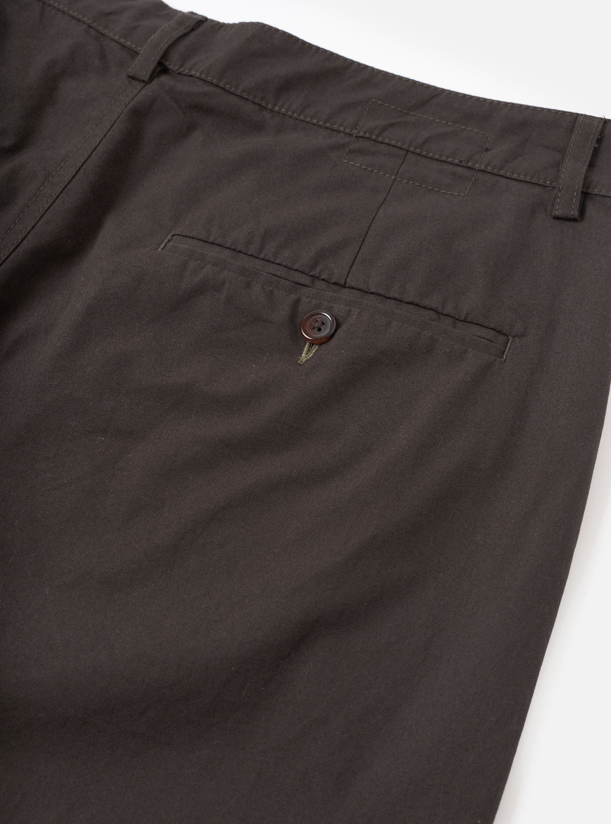 Detailed close-up view of the Brown Micro Canvas Military Chino set against a simple white background. The image focuses on the waist construction, button closure, belt loops, and fine micro-canvas weave of the brown cotton trousers.