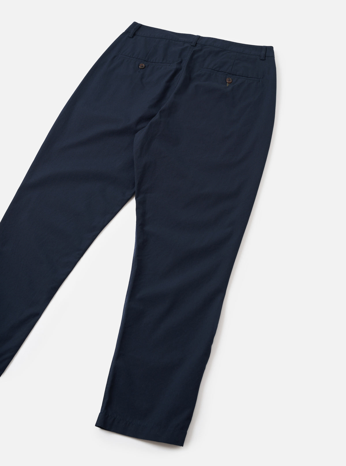 Rear view image of the Navy Micro Canvas Military Chino presented on a plain white studio background. The shot emphasizes the back welt pockets, clean seam details, waistband structure, and straight fit of the dark navy cotton trousers.