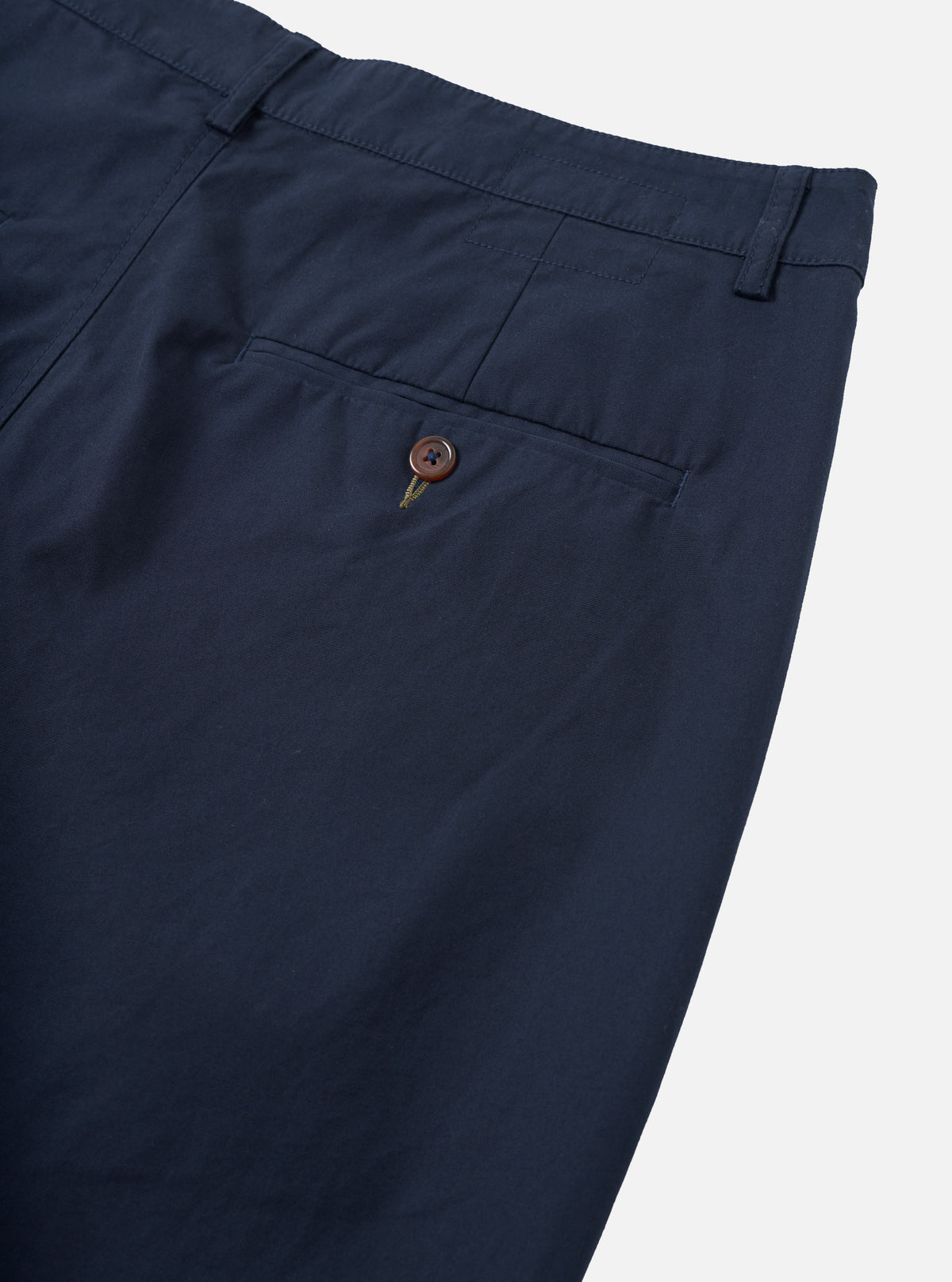 Detailed close-up shot of the Navy Micro Canvas Military Chino set on a plain neutral background. The photo focuses on the waist fastening, belt loops, fly details, and fine cotton micro-canvas weave in a classic navy blue shade.